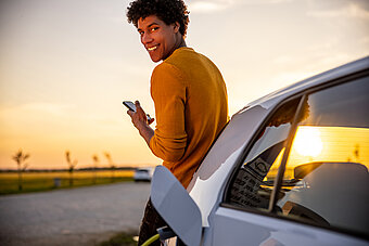 E-Auto Ladekarte. Mann steht an ladenden E-Auto