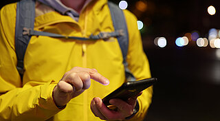 Westfalen Tankstellen. Person in gelber Jacke mit Handy