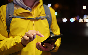 Westfalen Tankstellen. Person in gelber Jacke mit Handy