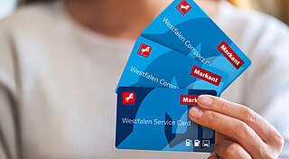 Westfalen Card. Frau hält verschiedene Westfalen Cards in der Hand