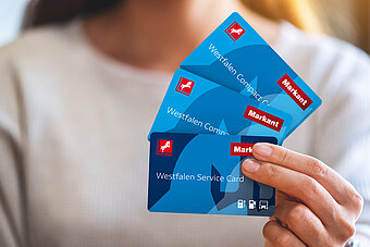 Westfalen Card. Frau hält verschiedene Westfalen Cards in der Hand