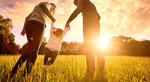 Energieversorgung mit Flüssiggas als Begleiter der Energiewende. Familie hat Spaß auf einem Feld im Sonnenuntergang.