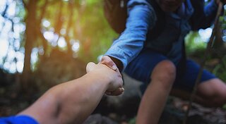 Hinweisgebersystem Westfalen Gruppe. Eine Person hilft einer anderen hoch