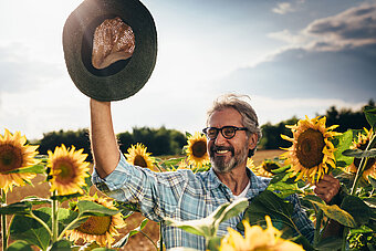 Flüssiggas und die Umwelt. Landwirt mit guter Laune im Sonnenblumenfeld
