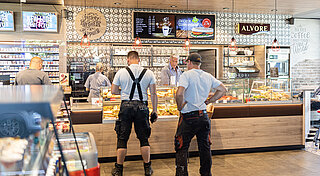 Tankstelle Shop. Kunden stehen an einer Kasse in einem Mobility Hub