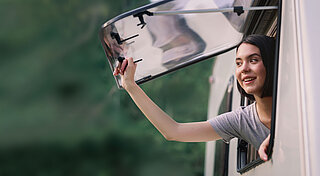 Wohnmobil. Frau am Fenster von einem Wohnmobil 