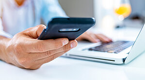 Westfalen Tankstellen Kundenportal. Mann sitzt mit Handy am Laptop