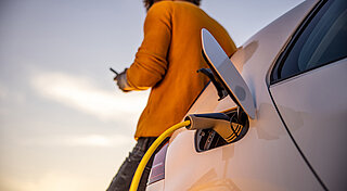E-Auto Ladekarte. Mann steht an ladenden E-Auto