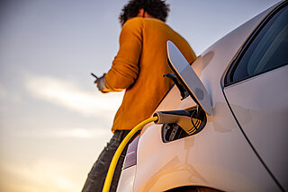 E-Auto Ladekarte. Mann steht an ladenden E-Auto